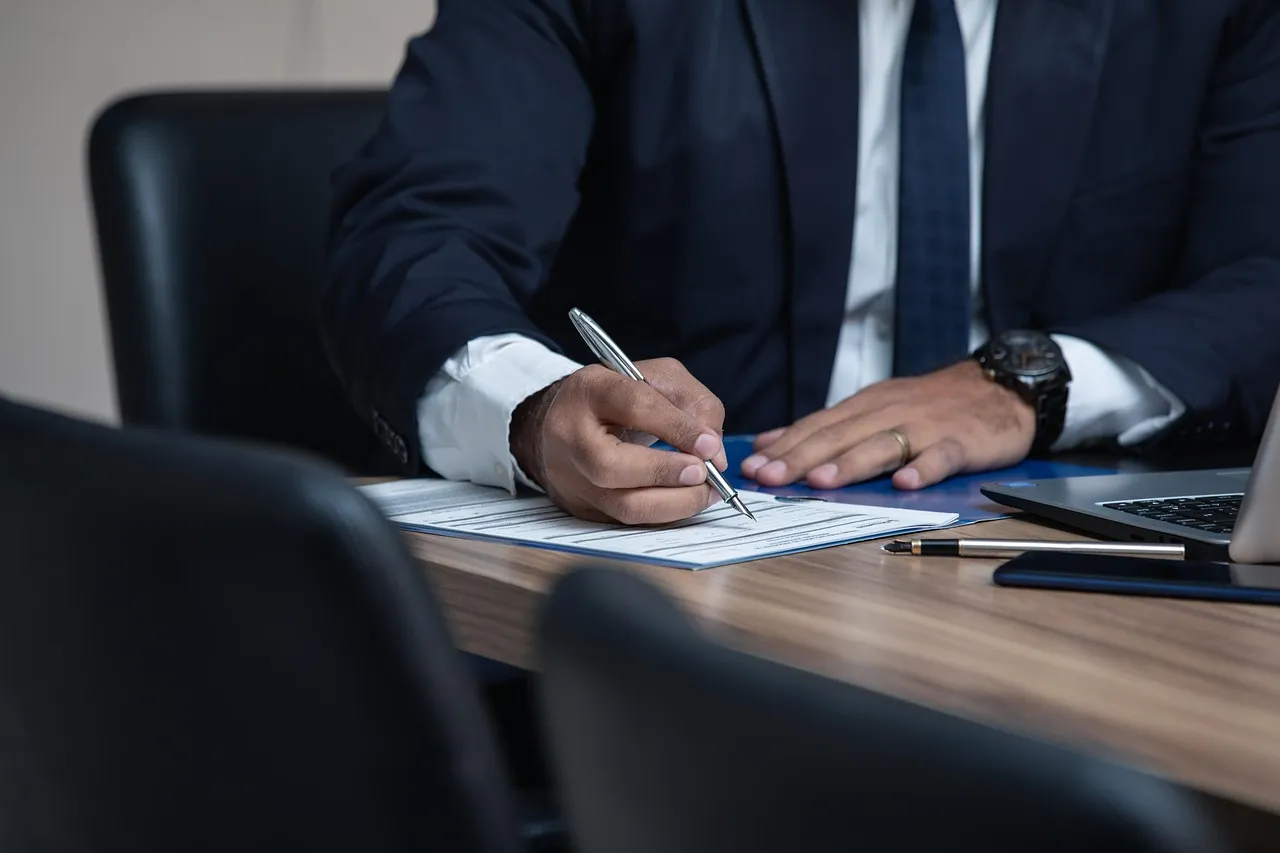 Professional in a suit reviewing and signing documents at a desk, illustrating compliance review of social media content